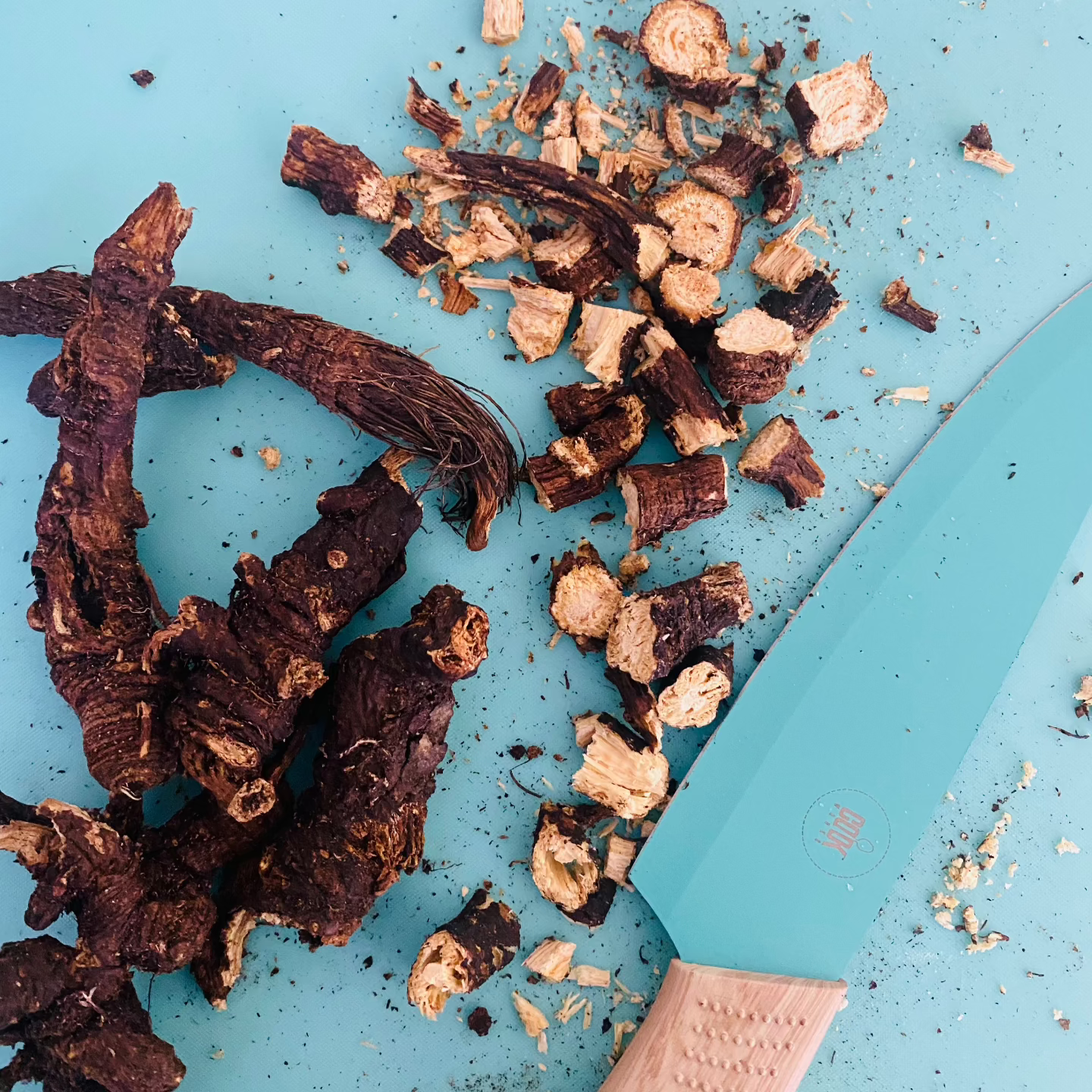 Wozani Osha root recovery supplement dried roots and chopped pieces next to a blue cutting knife
